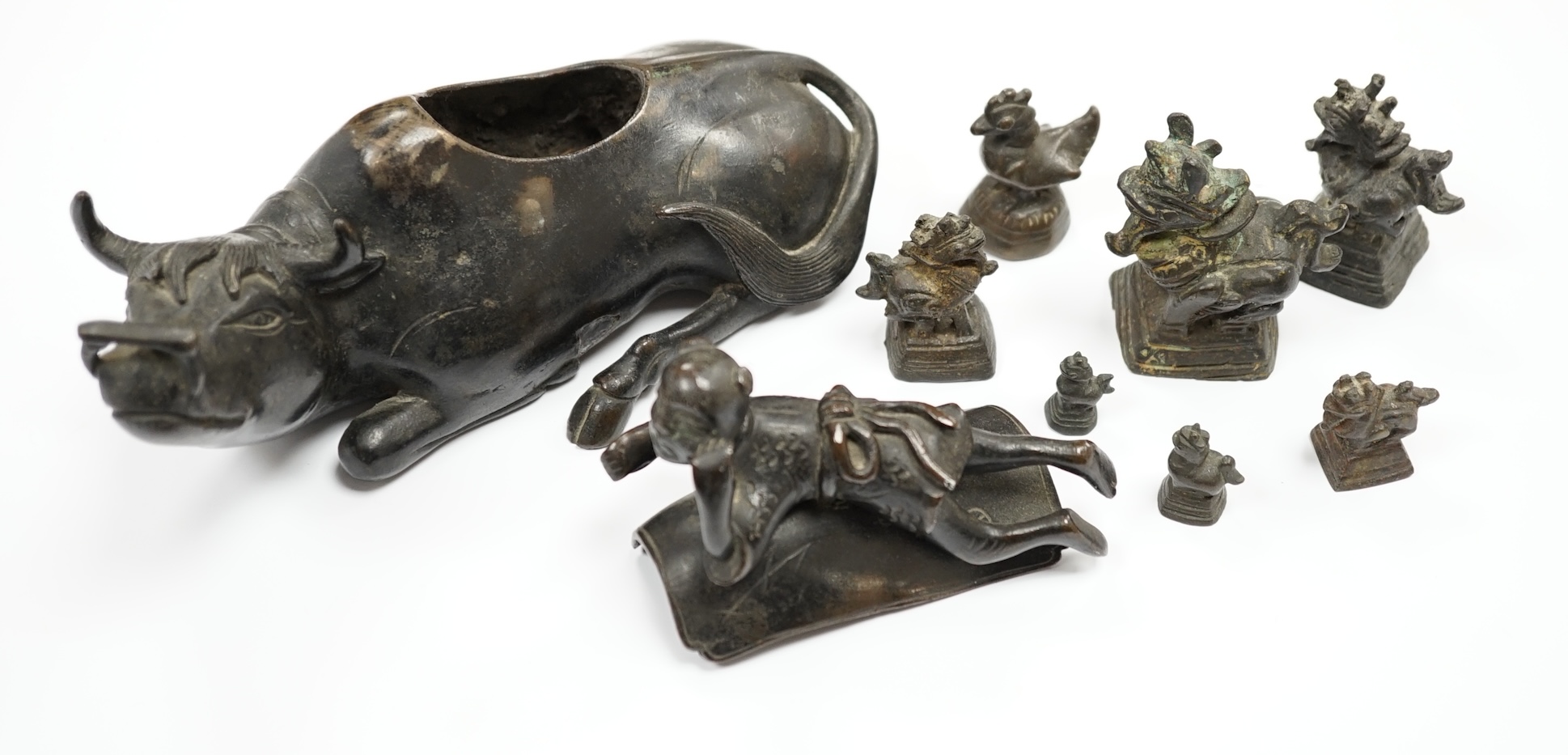 A Chinese bronze ‘water buffalo’ box and cover, Qing dynasty, and a set of Burmese opium weights, largest 18cm long